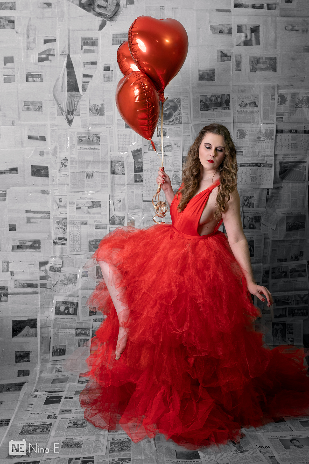 Frau it roten Herz-Luftballons vor Zeitungshintergrund