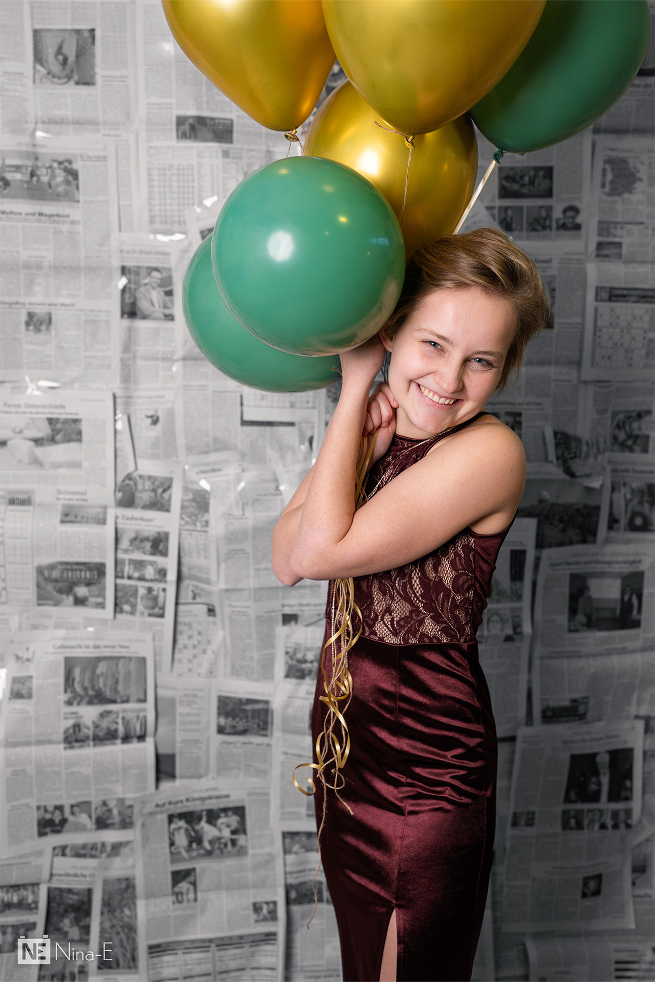 Person hält Heliumballons fest vor Zeitungshintergrund